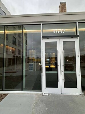 A modern building entrance with a glass facade and a door marked with the number 4647. - Sleepover | Urban Studio + Gym/Sauna - Omaha (Omaha)