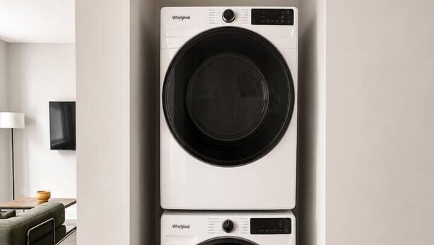 A laundry room with two stacked Whirlpool front-loading washers. - Sleepover | Airy Studio + Gym/Sauna - Omaha (Omaha)