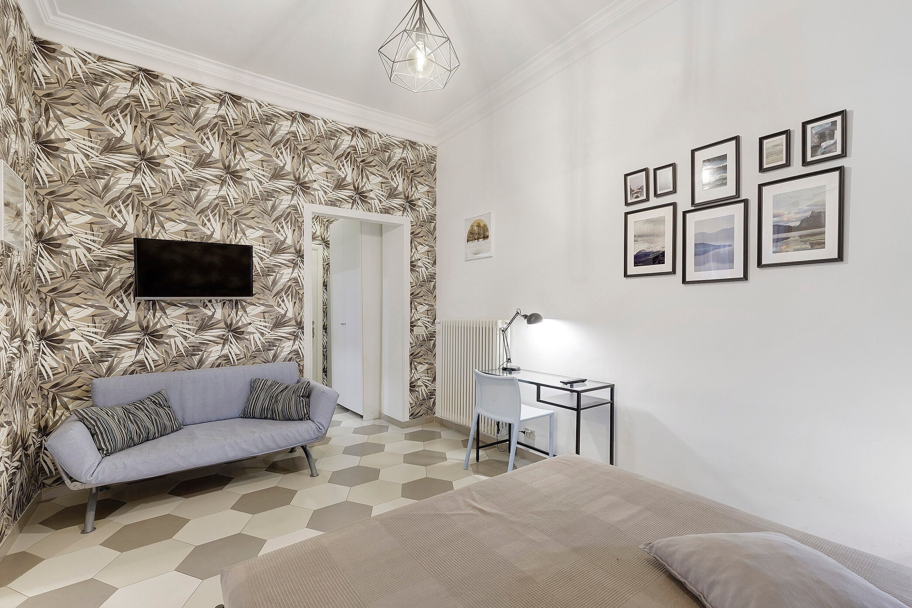 A modern bedroom with a sofa, a desk, and a bed.