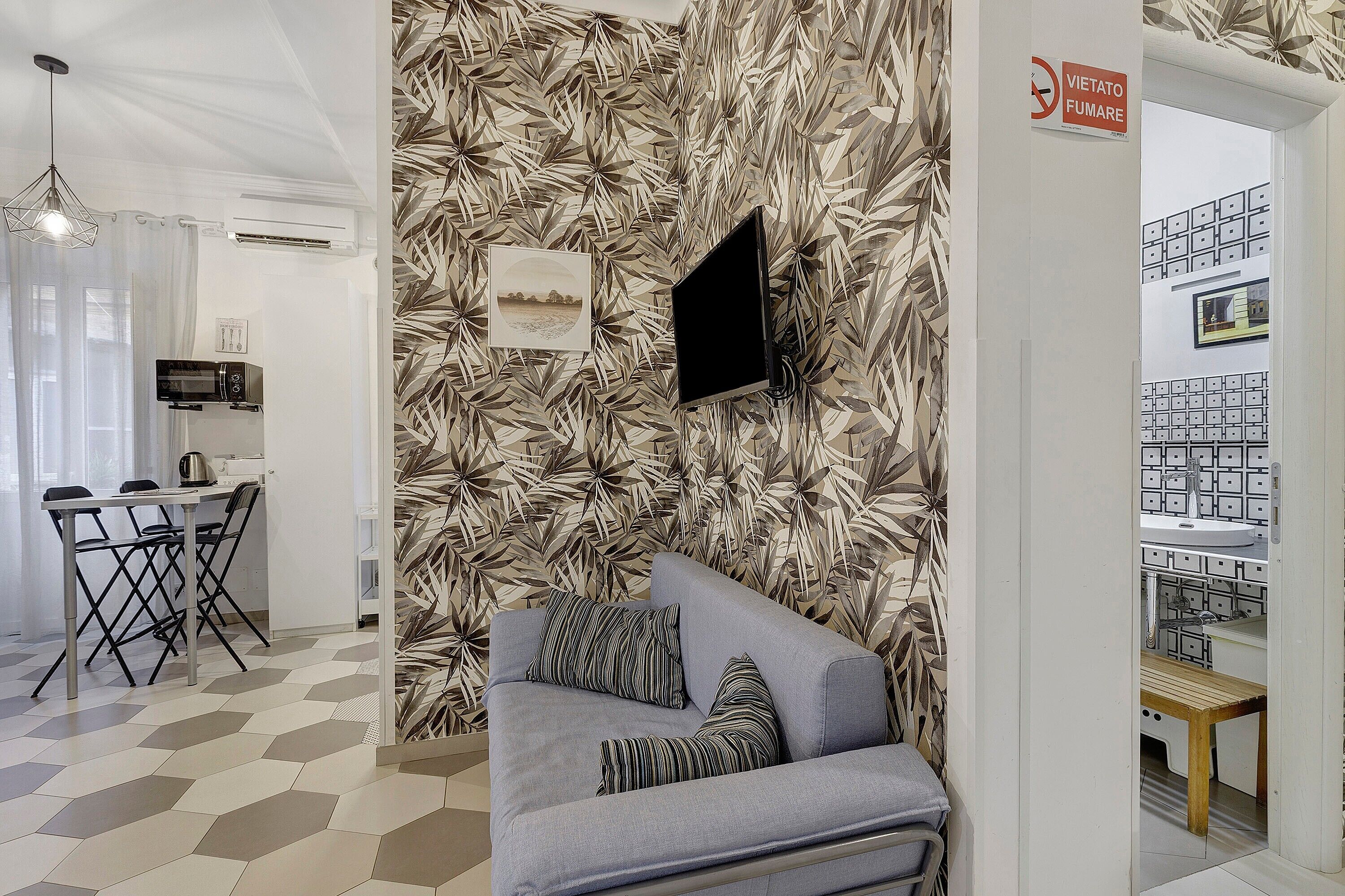 A modern interior with a sofa, a flat-screen TV, and a patterned wall.