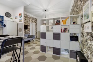Ein modernes Zimmer mit einem sechseckig gefliesten Boden, einem weißen Bücherregal und einer Essecke mit Tisch und Stühlen.