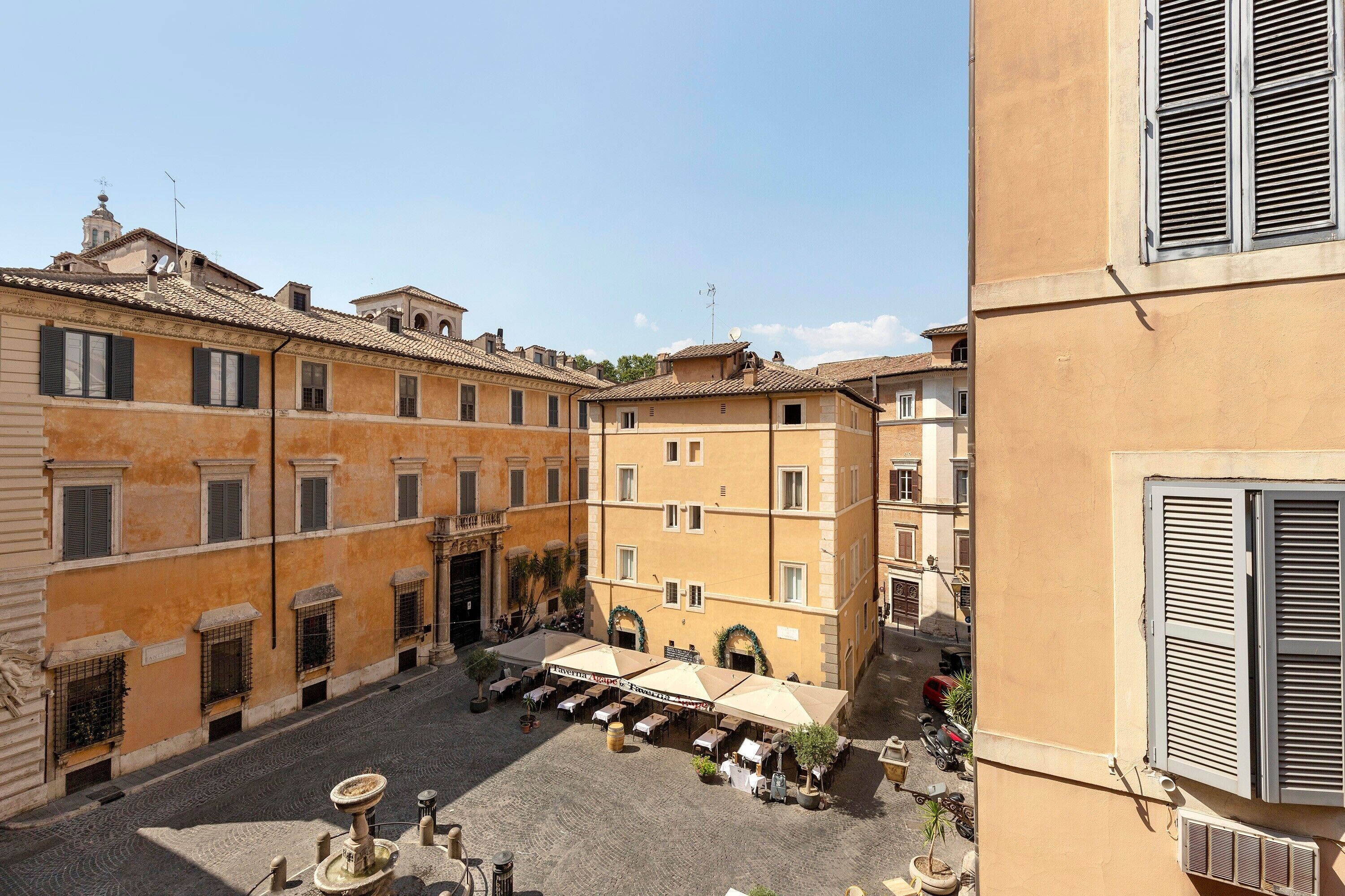 A courtyard with buildings, outdoor seating, and a fountain.