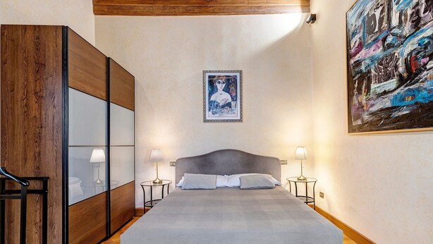 Ein Schlafzimmer mit einem Bett, Nachttischlampen, einem Kleiderschrank und einem Bild an der Wand.