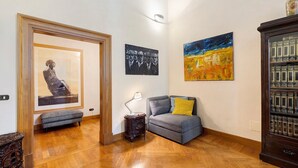 Ein Korridor mit Holzboden, einer Bank, einem Tisch mit Lampe und einem Sofa mit Kissen.