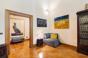 Ein Korridor mit Holzboden, einer Bank, einem Tisch mit Lampe und einem Sofa mit Kissen.