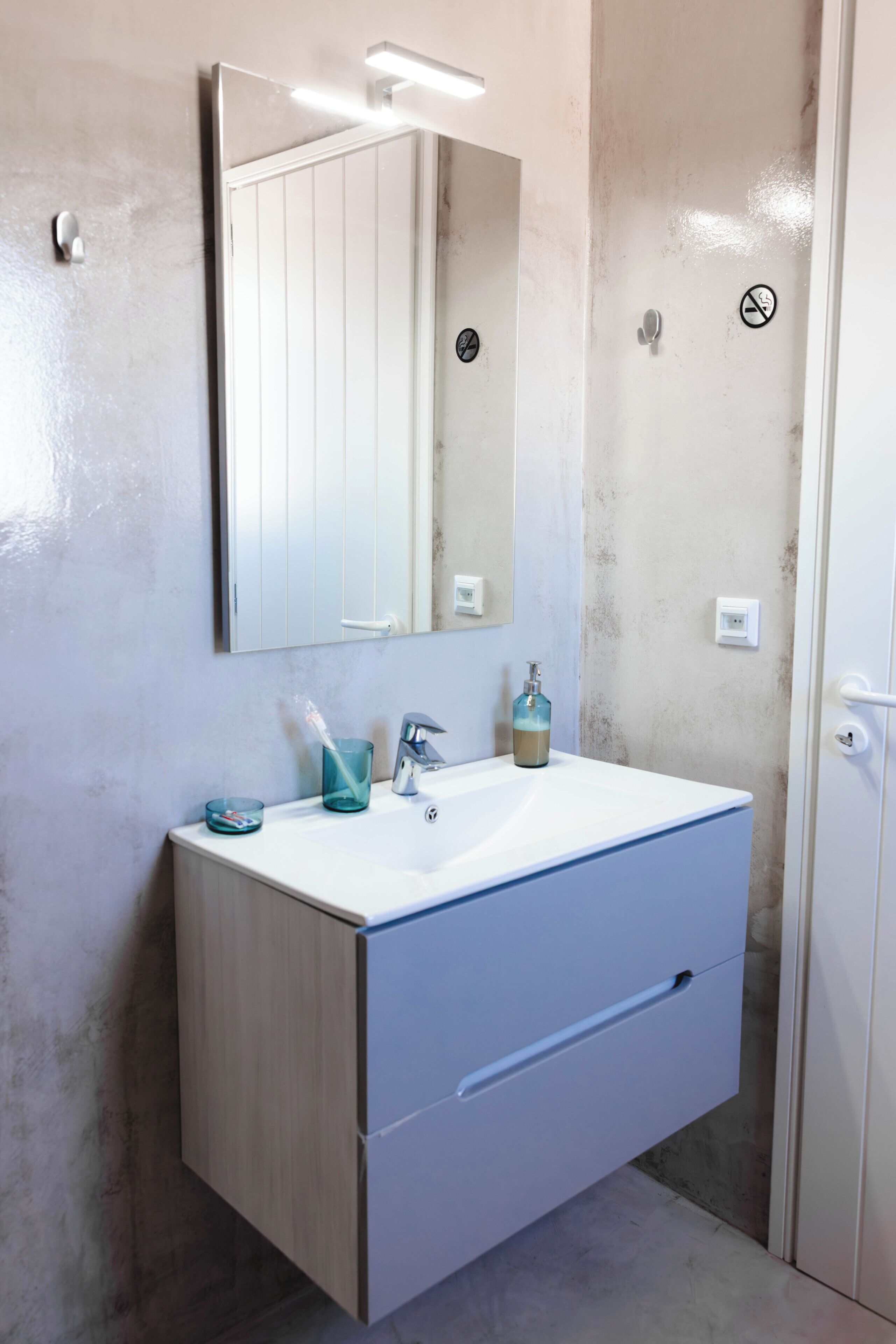 A bathroom with a white sink, a mirror, a towel rack, and a shower door.