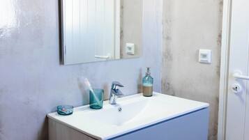 A bathroom with a white sink, a mirror, a towel rack, and a shower door.