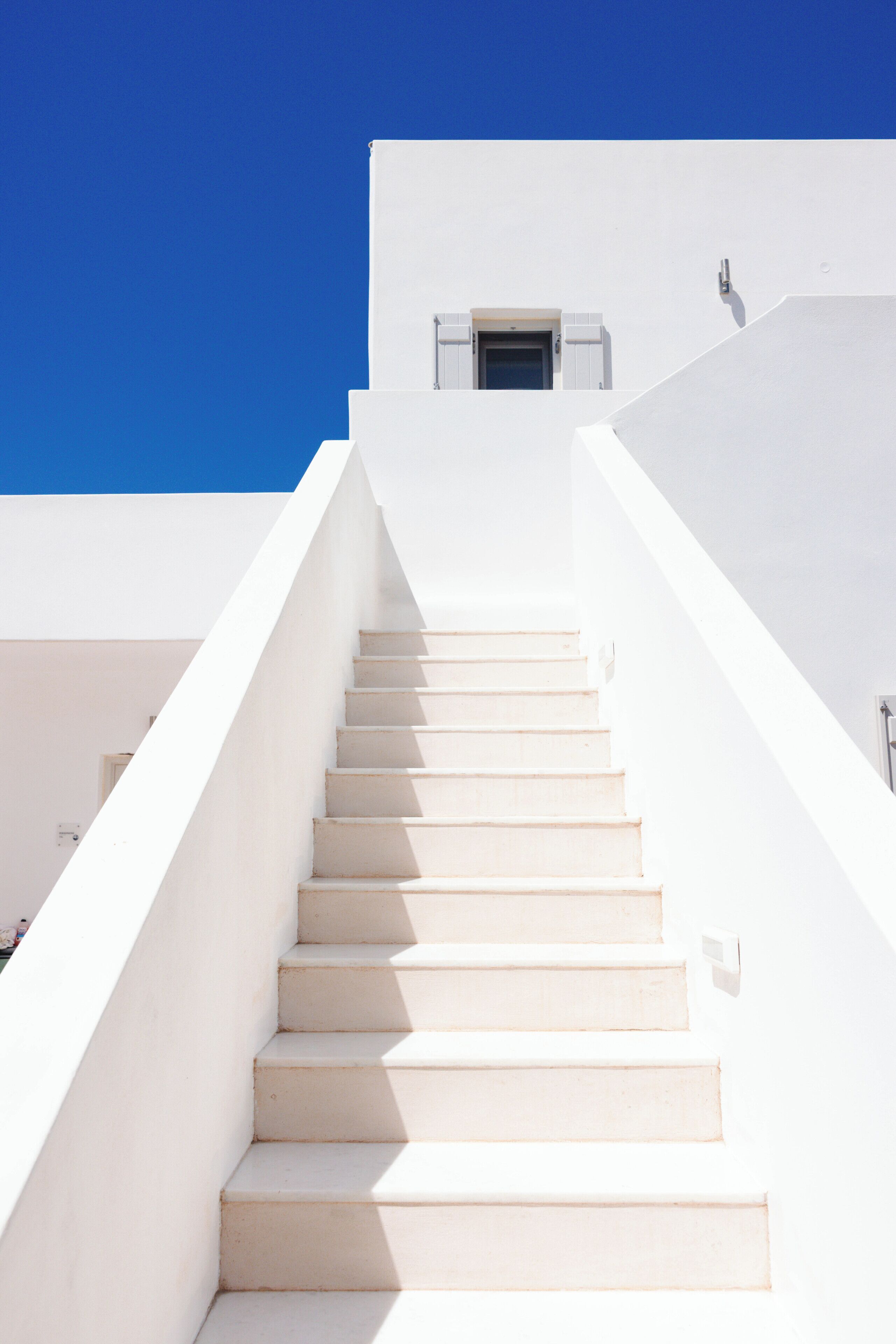 A white staircase leading to a building with a small window.