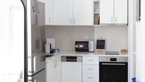 Uma cozinha moderna com armários brancos, eletrodomésticos de aço inoxidável e bancada clara.