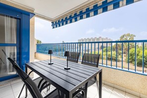 A balcony with a table and chairs, a view of a building, and a blue railing. - Patacona Pure. WiFi+PK+A/C+Pool (Alboraya / Alboraia)