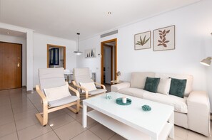 A modern living room with a white sofa, two armchairs, a coffee table, and a dining area in the background. - Patacona Pure. WiFi+PK+A/C+Pool (Alboraya / Alboraia)