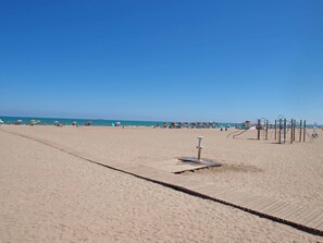 A sandy beach with a wooden boardwalk, beach umbrellas, and a playground structure. - Patacona Pure. WiFi+PK+A/C+Pool (Alboraya / Alboraia)