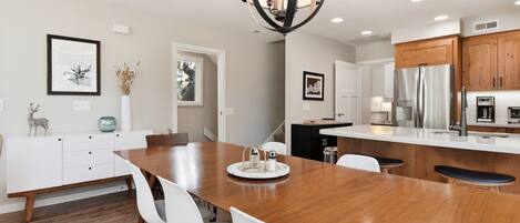 A modern kitchen with a wooden island, white cabinetry, and stainless steel appliances.