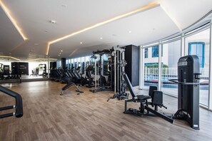 A modern gym with various exercise equipment, large windows, and a wooden floor. - Modern Studio with Private Pool and Balcony (Dubai)