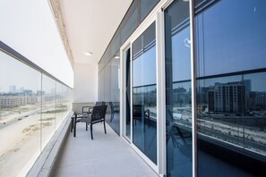 A balcony with a view of a cityscape, featuring a table and chairs. - Modern Studio with Private Pool and Balcony (Dubai)