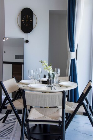 A dining area with a round table set for four, surrounded by chairs with a woven seat design. - Modern Studio with Private Pool and Balcony (Dubai)