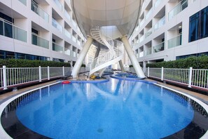 A modern indoor swimming pool with a central spiral staircase, surrounded by balconies and a white fence. - Modern Studio with Private Pool and Balcony (Dubai)