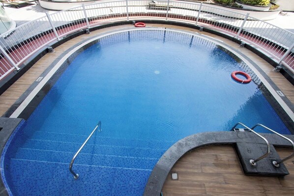 A large, curved swimming pool with a wooden deck and metal railings. - Modern Studio with Private Pool and Balcony (Dubai)