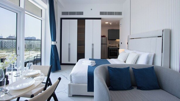 A modern hotel room with a large bed, a dining area, and a kitchenette. - Modern Studio with Private Pool and Balcony (Dubai)