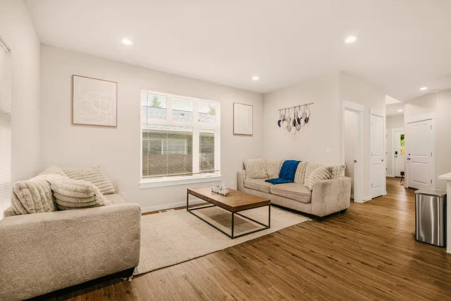 A modern living room with a sofa, coffee table, and a window with blinds.