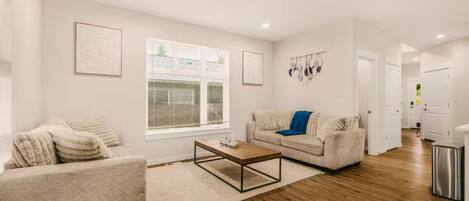 A modern living room with a sofa, coffee table, and a window with blinds.