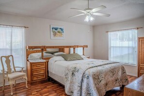 A bedroom with a wooden bed, a chair, a nightstand, a ceiling fan, and a window with blinds. - Cozy & Comfortable 3-Bed 2-Bath Sleeps 7 (Valrico)