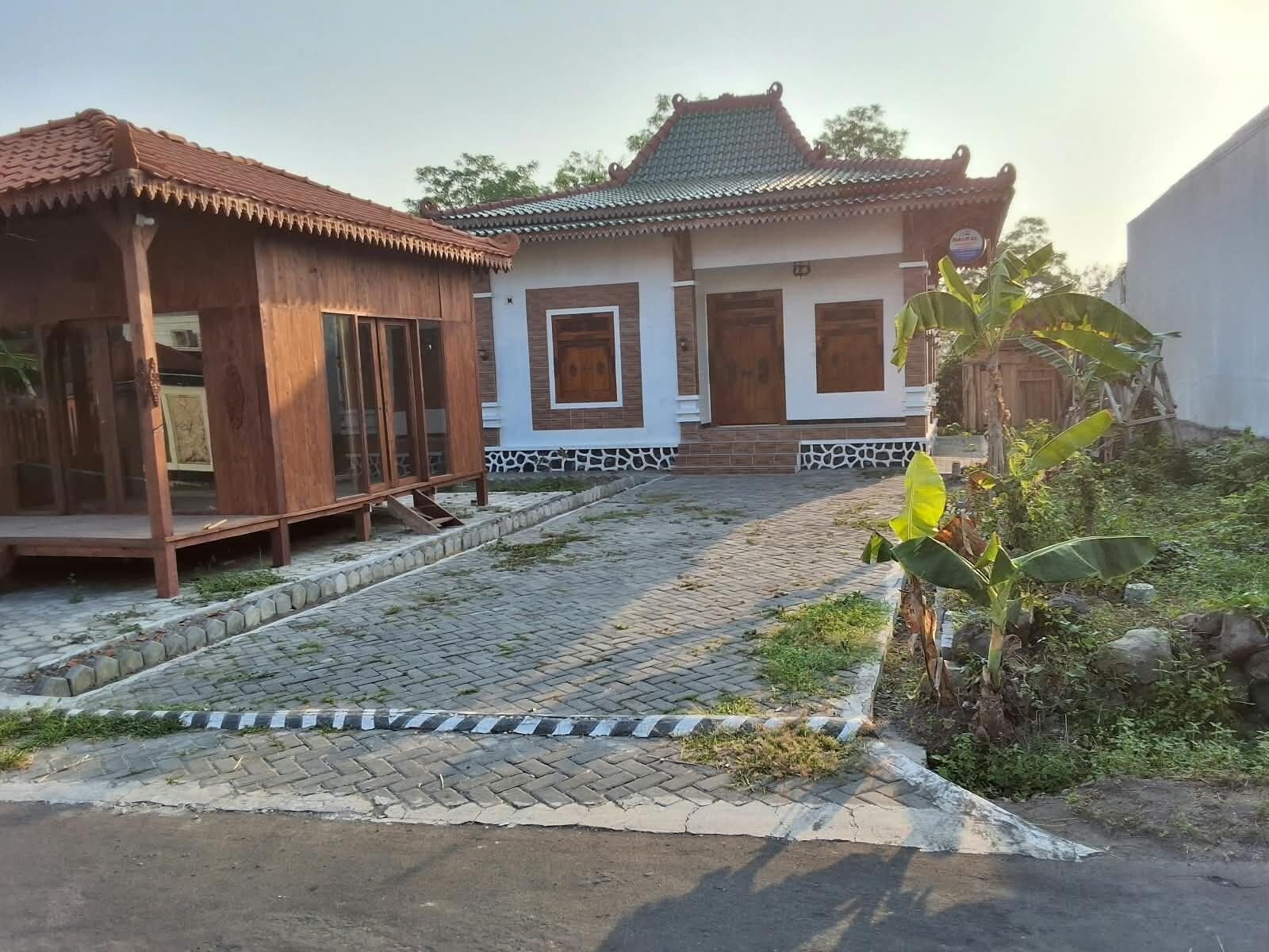 A traditional house with a tiled roof, a wooden porch, and a paved entrance.