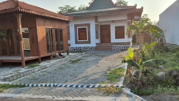 A traditional house with a tiled roof, a wooden porch, and a paved entrance.