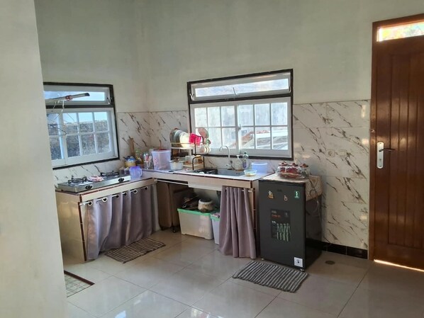 A compact kitchen with a gas stove, a refrigerator, and a window providing natural light.