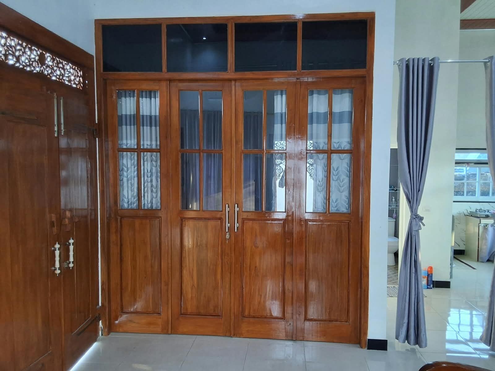 Una habitación con un gran armario de madera, un vidrio y una cortina.