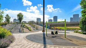 A playground with slides and swings, surrounded by a paved area and greenery. - The Weekender | Cozy Bridgeland Retreat | Sleeps 2 (Calgary)