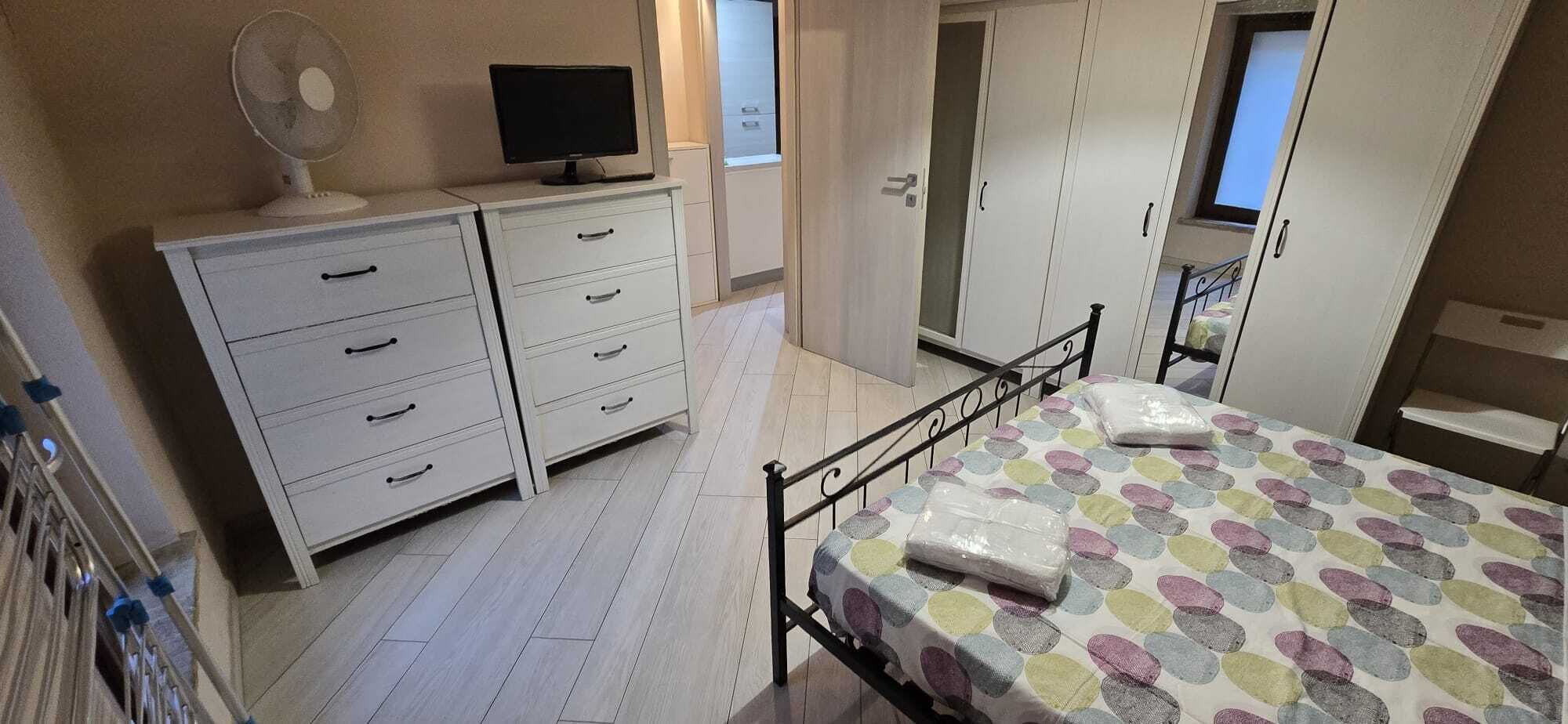A bedroom with a bed, a dresser, a television, and a window.