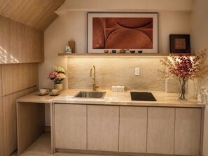 A modern kitchen with a built-in sink, a countertop, and a wooden cabinet. - Aurora Stay Inn Saigon (Ho Chi Minh City)