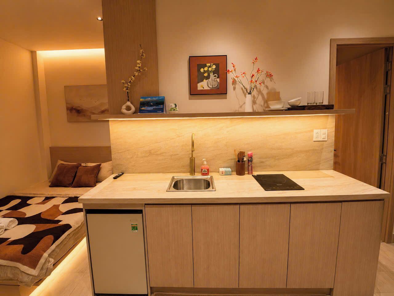 A compact kitchen with a built-in sink, a small refrigerator, and a countertop with a toaster.