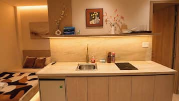 Una cocina compacta con un lavamanos empotrado, un refrigerador pequeño y una encimera con un tostador.