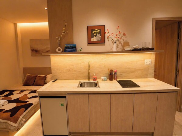 A compact kitchen with a built-in sink, a small refrigerator, and a countertop with a toaster. - Aurora Stay Inn Saigon (Ho Chi Minh City)