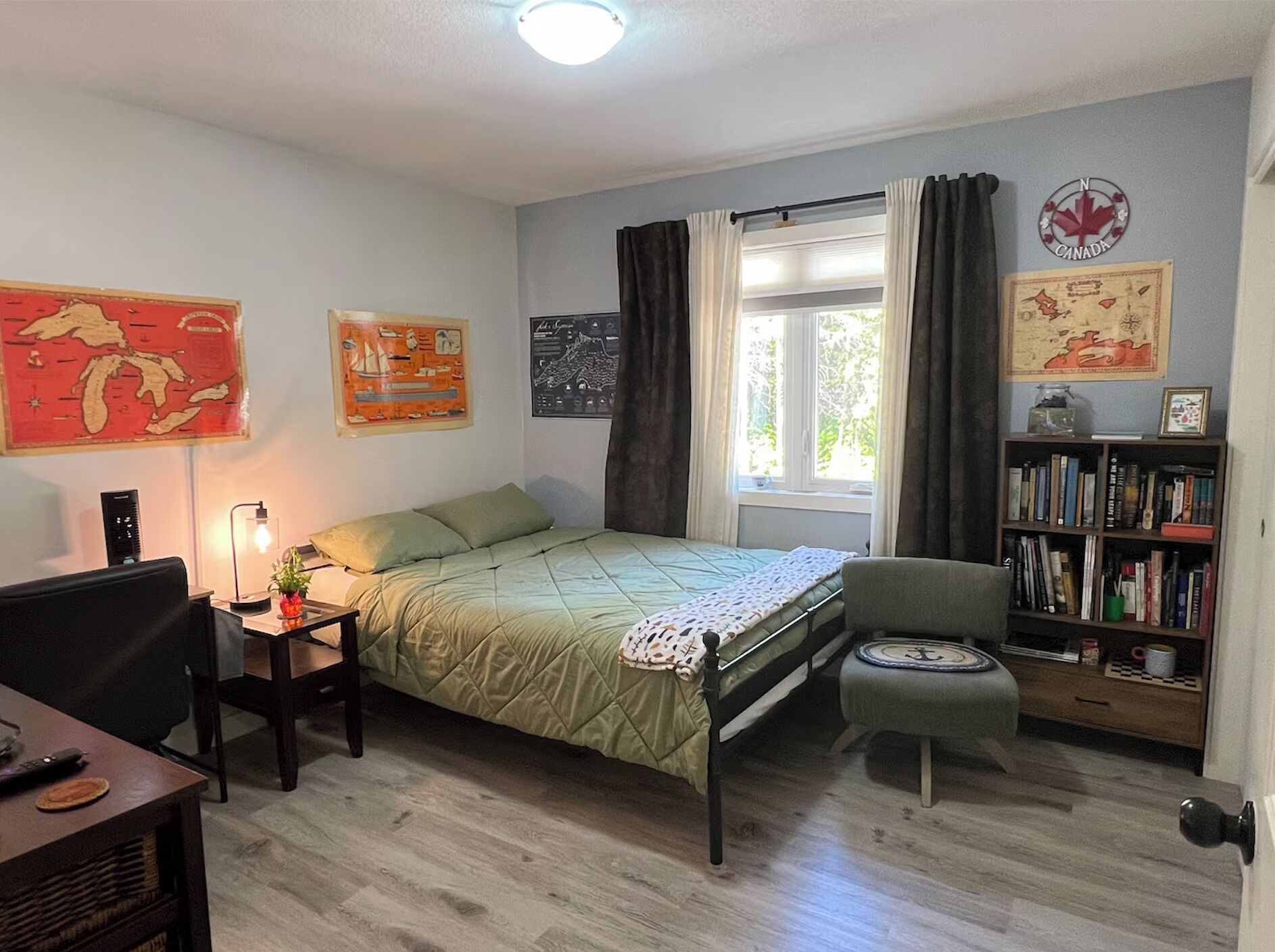 A bedroom with a bed, a desk, a chair, a bookshelf, and a window with curtains.
