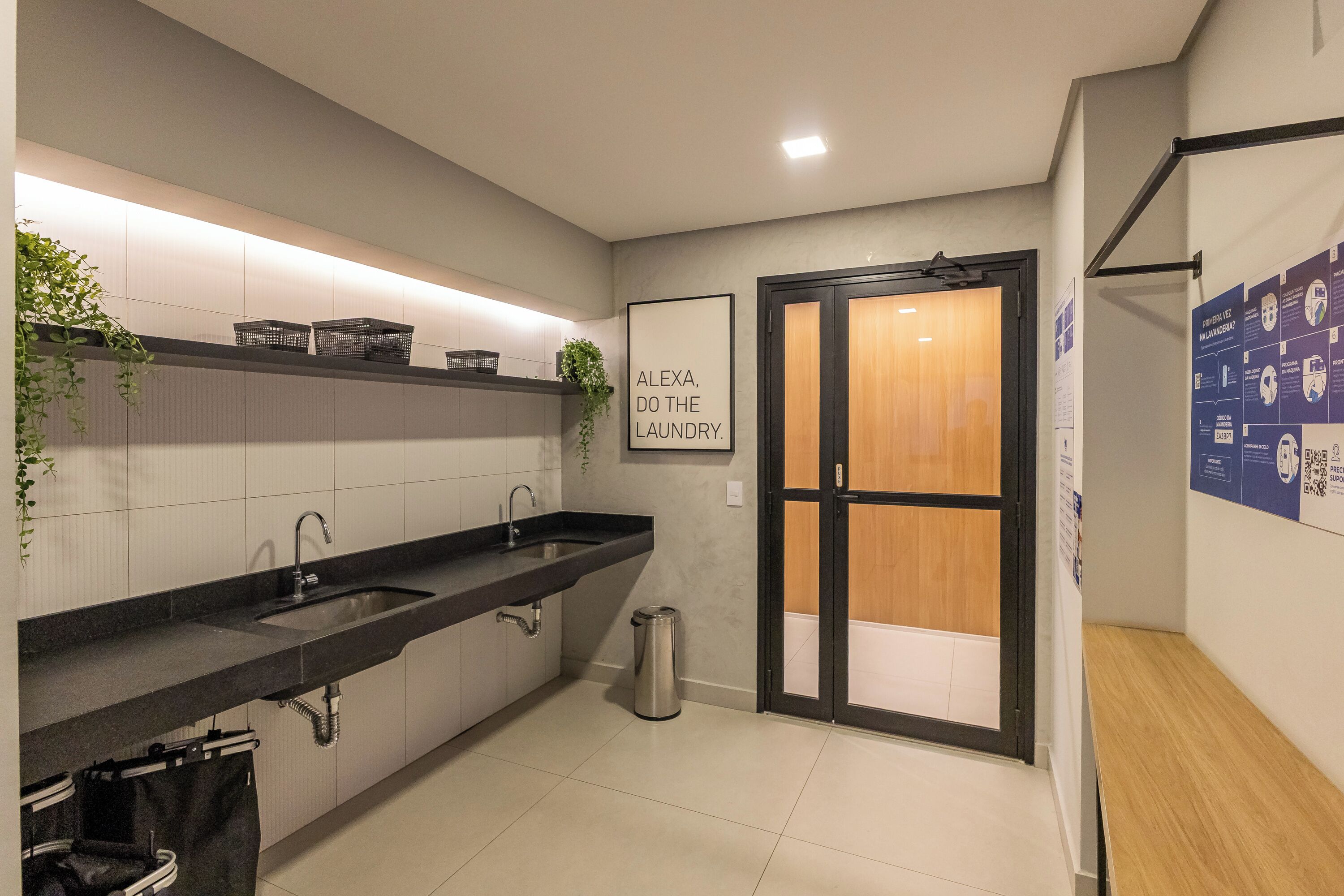 A modern bathroom with a black sink, white tiles, a wooden door, and a poster on the wall.