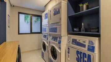 Une laverie équipée de plusieurs machines à laver et de plusieurs séchoirs, tous portant la mention « SEGA ».
