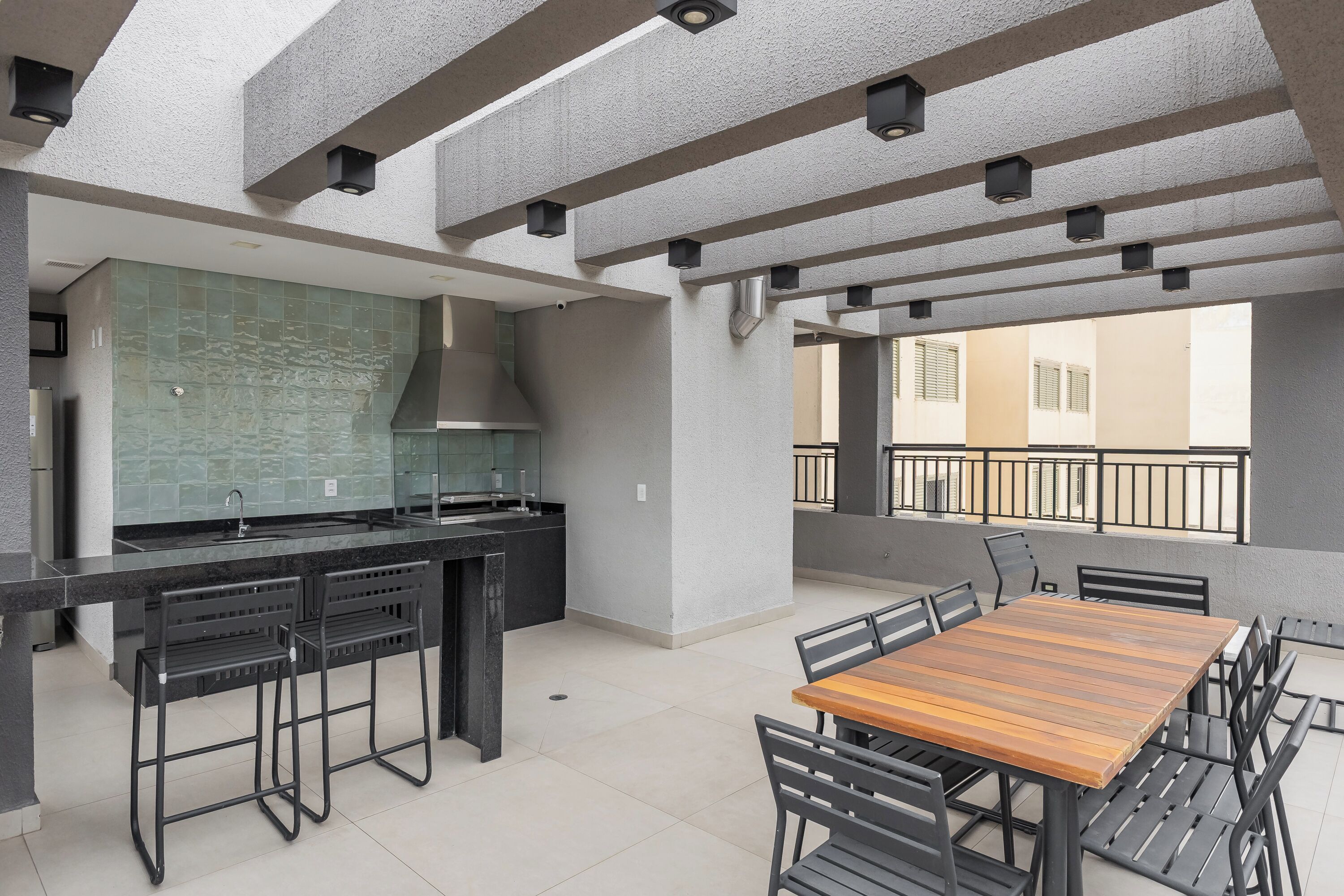 A modern kitchen with a large island, a dining area with a wooden table and chairs, and a balcony with a railing.