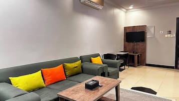 Una sala moderna con un sofá, una mesa de centro y un televisor de pantalla plana montado en la pared.