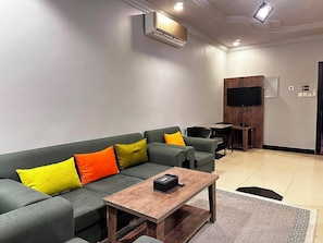 Una sala moderna con un sofá, una mesa de centro y un televisor de pantalla plana montado en la pared.
