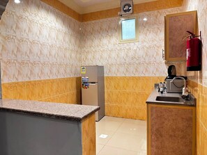 Cocina compacta con refrigerador, pileta y extintor.