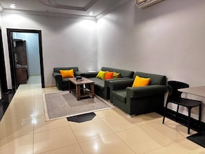 A modern living room with a sofa set, a coffee table, and a dining table. - Bawabat Al Worood Serviced Apartments (taif)