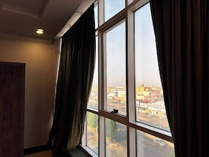 Una habitación con un ventanal grande, cortinas y vista panorámica de la ciudad.