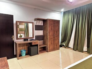 A room with a wooden desk, a mirror, a wardrobe, and a curtain.