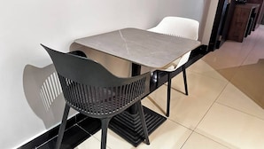 A dining area with a table and chairs, a black chair with a unique design, and a tiled floor.