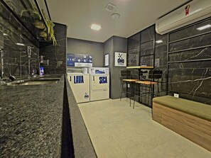 Une salle de bain moderne avec un comptoir en marbre, un espace douche et un coin salon avec un banc.