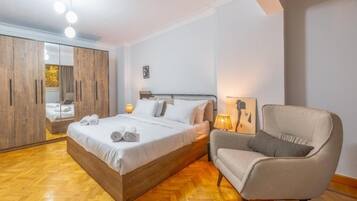 Un dormitorio con cama, mesita de noche, silla, armario y espejo.