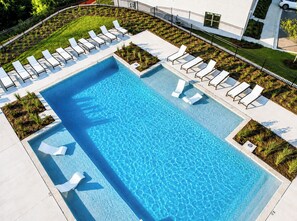 A rectangular swimming pool with clear blue water, surrounded by white lounge chairs and small plants. - The Grove Haven, 2mi-SQ+Pool by Velvet Ditch Villas (Oxford)